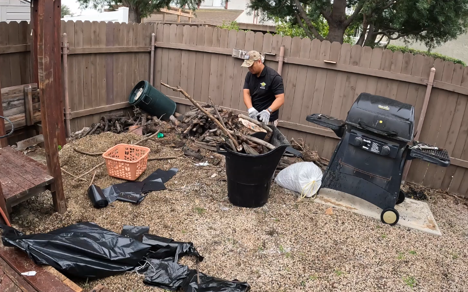 Junk Removal Worker Putting Branches into Garbage Bin in Huntington Beach, CA