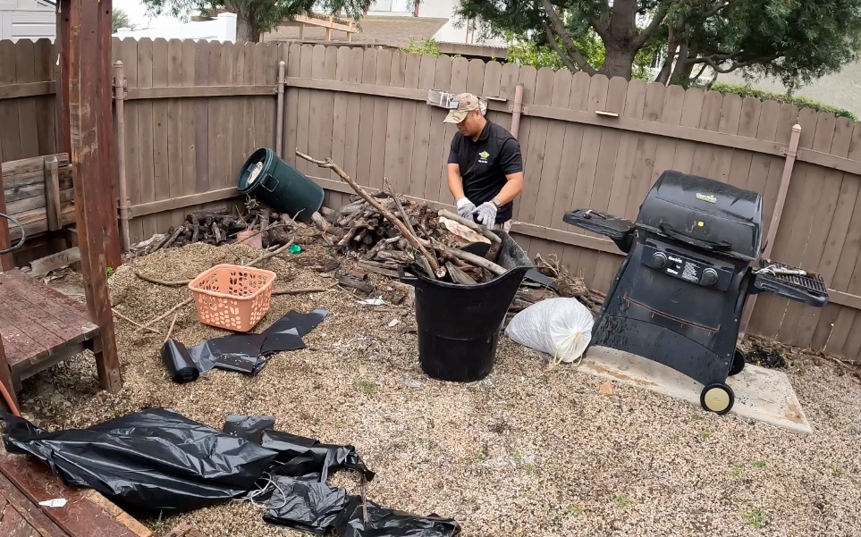 Junk Removal Worker Cleaning Up Sticks in Backyard in Long Beach, CA